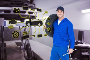 Confident mechanic carrying tire against auto repair shop